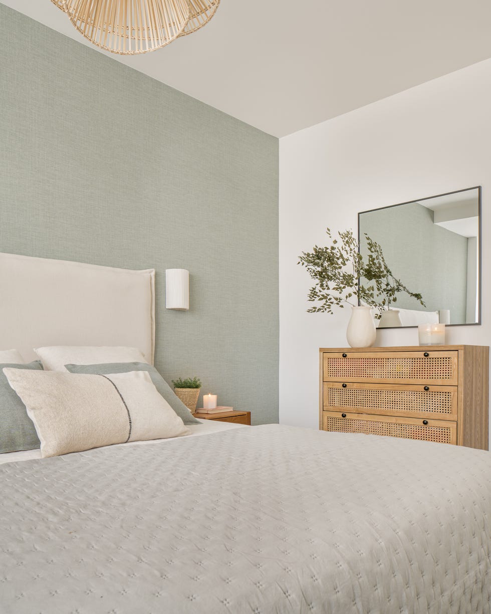 cama con cabecero de lino blanco y cómoda de madera y rejilla
