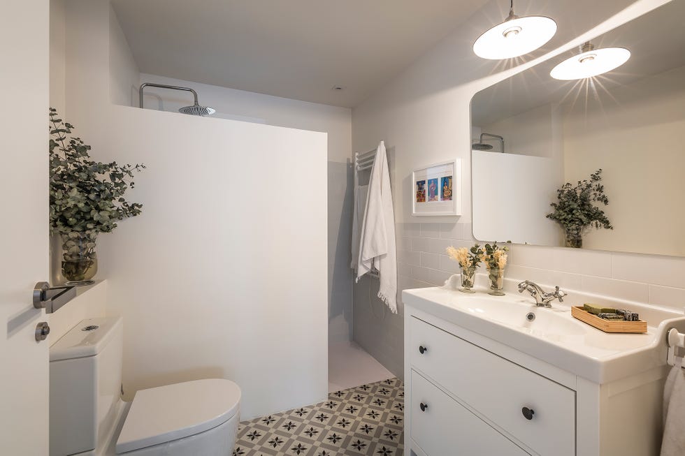 baño decorado en color blanco con ducha de obra y suelo de azulejos