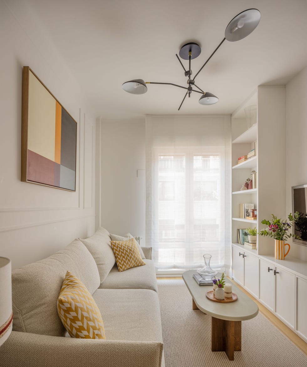 salón con sofá tapizado, mesa de centro ovalada y mueble de tv blanco