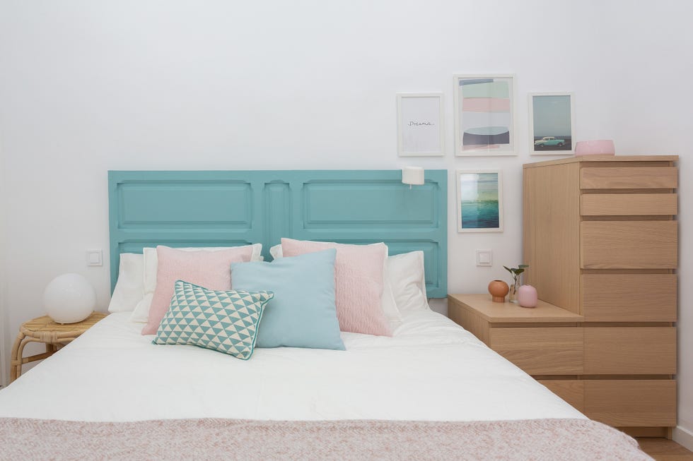 dormitorio de estilo nórdico con puerta pintada de azul turquesa como cabecero