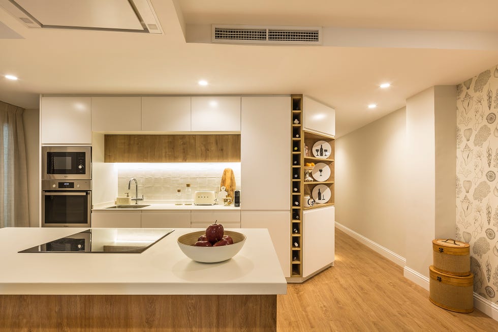 cocina abierta moderna con isla central de madera y encimera blanca a juego con los armarios sin tiradores