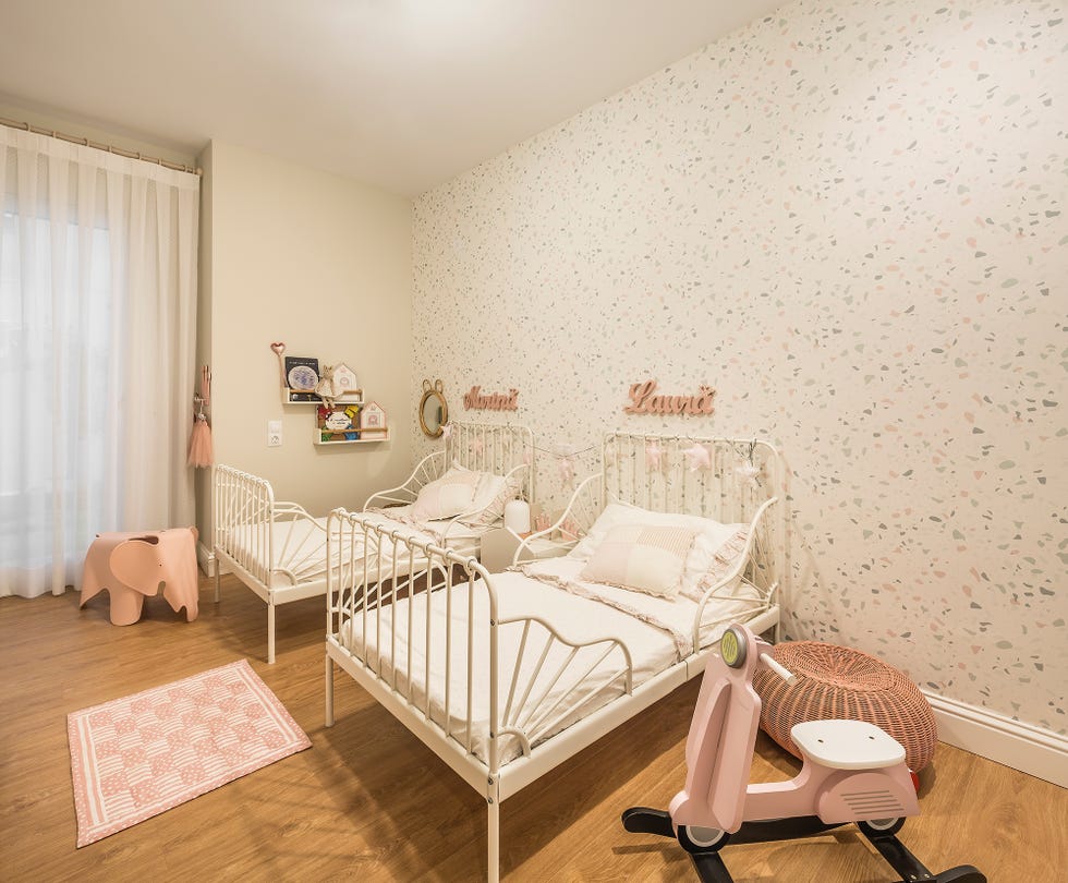 dormitorio infantil con dos camas de forja blanca y papel pintado con efecto terrazo
