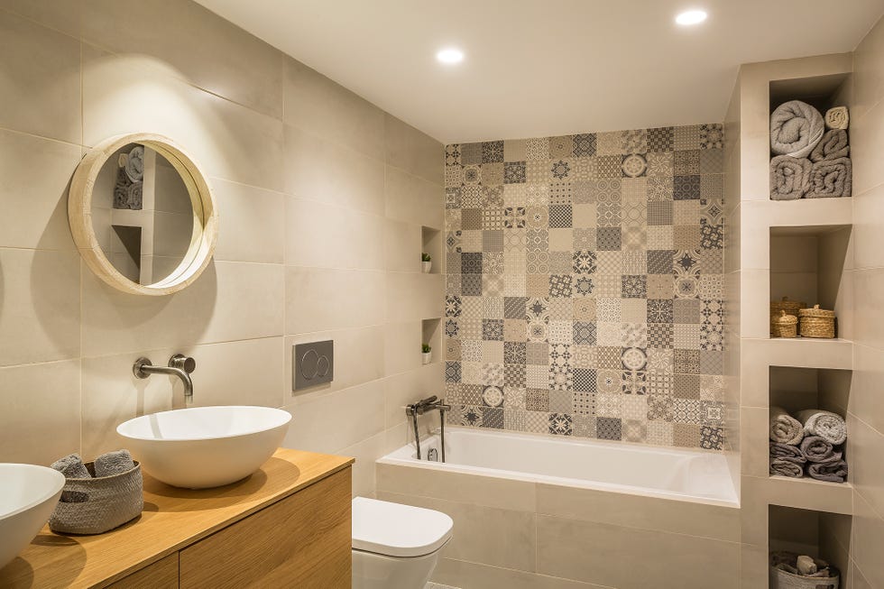 baño con bañera y pared de azulejos en mosaico en tonos grises