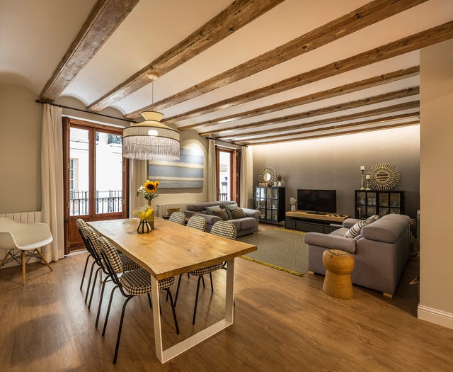 salón comedor decorado en tonos neutros con vigas de madera vistas