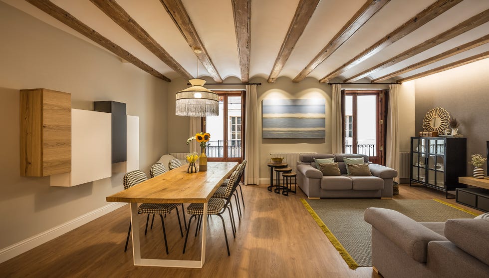 salón comedor decorado en tonos neutros con vigas de madera vistas