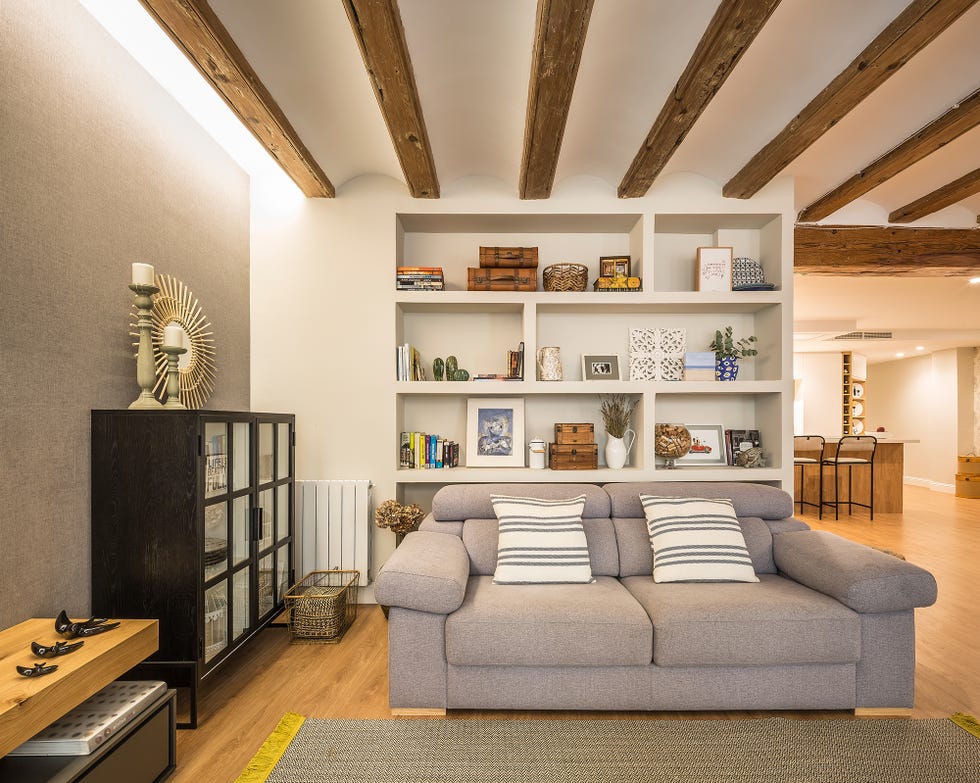 salón abierto al comedor y a la cocina decorado con un sofá gris y vigas de madera vistas