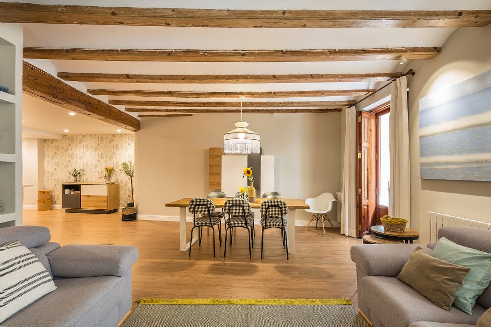 comedor abierto al salón y a la cocina con mesa de madera y sillas tapizadas con tela de cuadros vichy