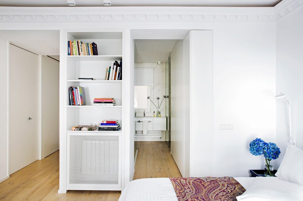 dormitorio con estantería de obra y baño en suite