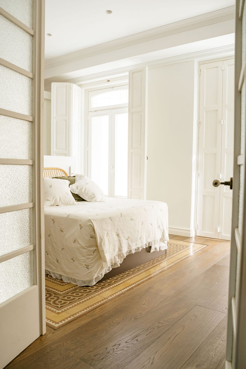 dormitorio con suelo de madera y contraventanas blancas