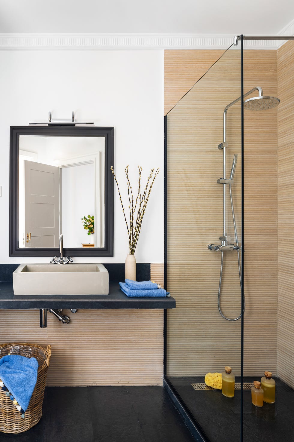 baño con ducha con suelo negro y paredes con revestimiento porcelánico de color natural