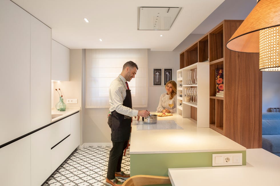 cocina moderna con isla central, armarios blancos y estantería de madera de nogal