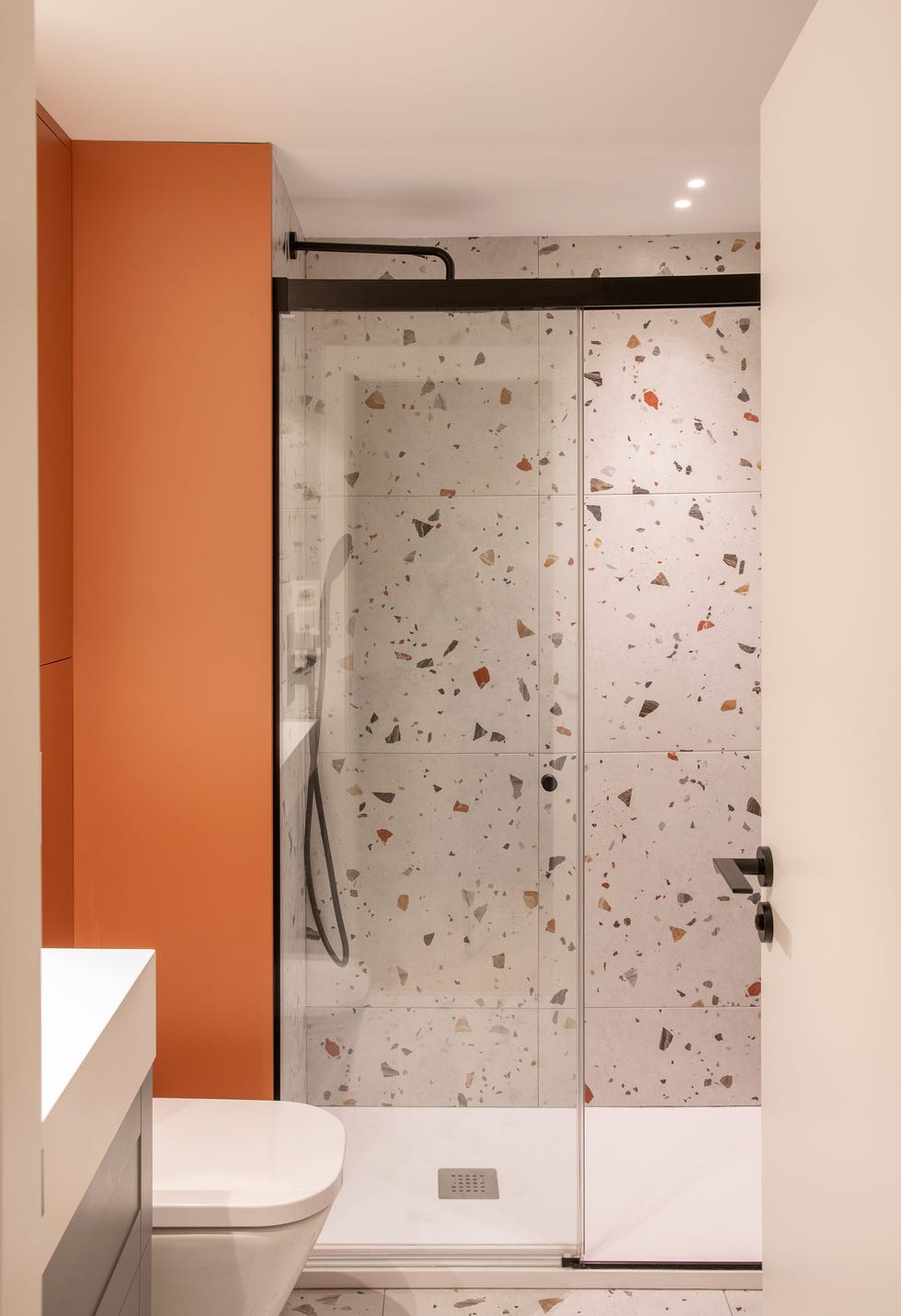baño moderno con azulejos de terrazo y armarios de color terracota