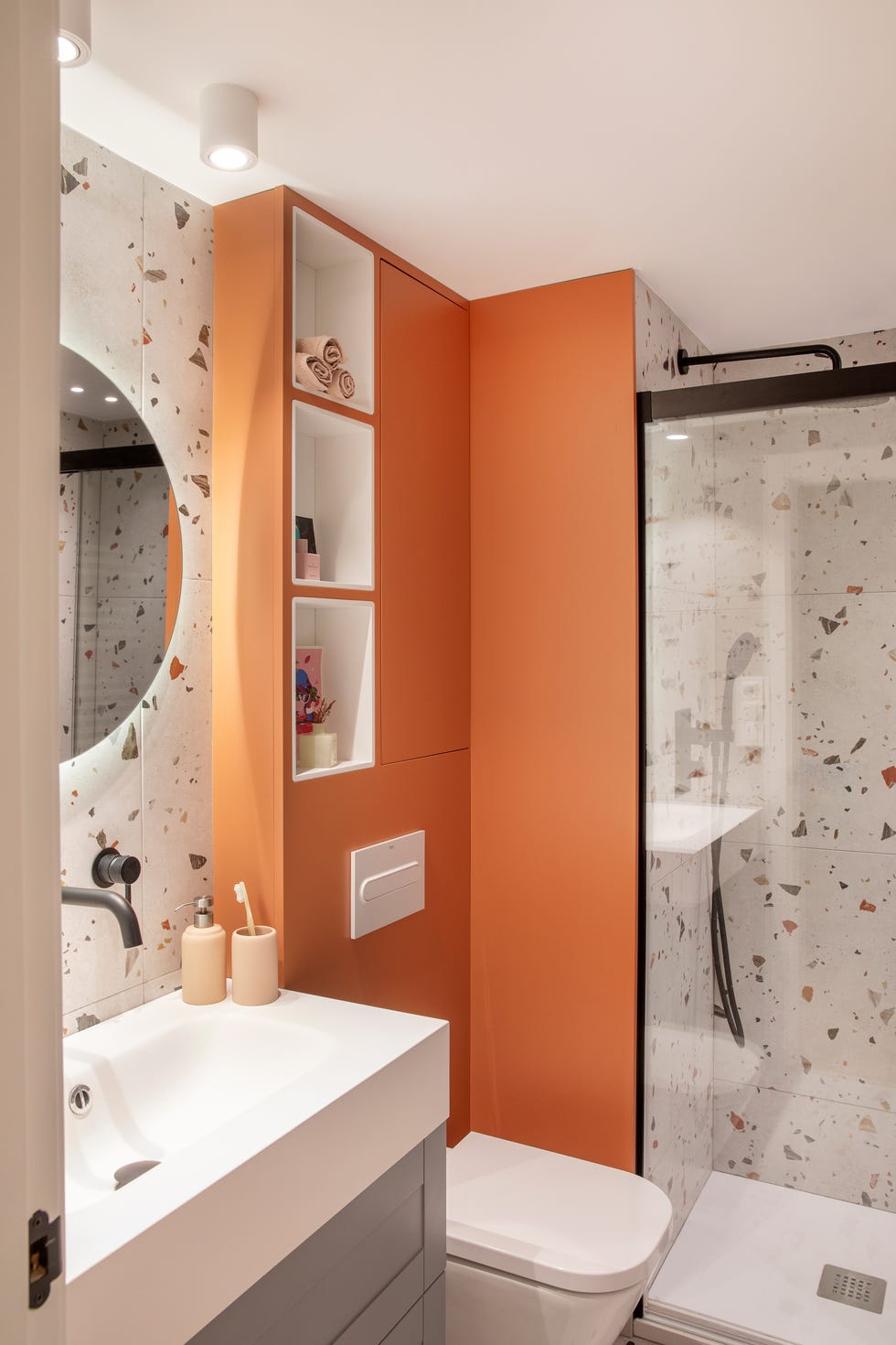 baño moderno con azulejos de terrazo y armarios de color terracota