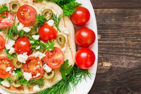 Pita with hummus, cheese, cherry tomatoes, olives and greenery