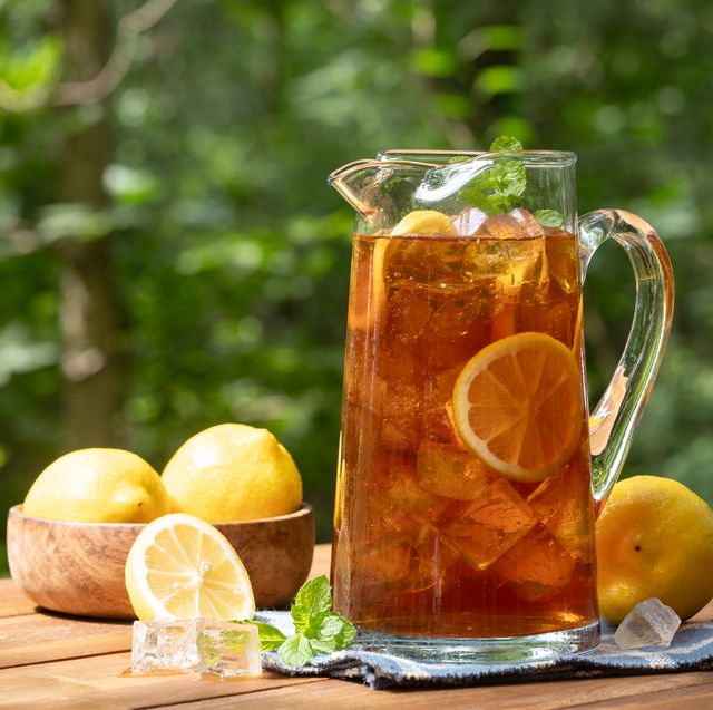 pitcher of ice tea with lemon slices and mint outdoors on wooden table