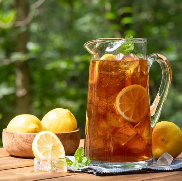 pitcher of ice tea with lemon slices and mint outdoors on wooden table