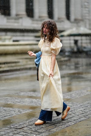 new york, new york   february 13 a guest wears a pale yellow puffy short sleeves long dress, a blue denim oversized jacket, a black shiny leather with nailed  studded star pattern handbag, rings, navy blue denim large pants, beige leather and camel soles ankle rain boot, outside ulla johnson, during new york fashion week, on february 13, 2022 in new york city photo by edward berthelotgetty images