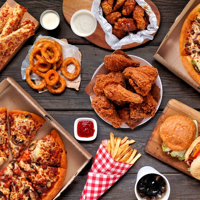 Buffet table scene of take out foods buffet table scene of take out or delivery foods. pizza, hamburgers, fried chicken and sides. above view on a dark wood background.