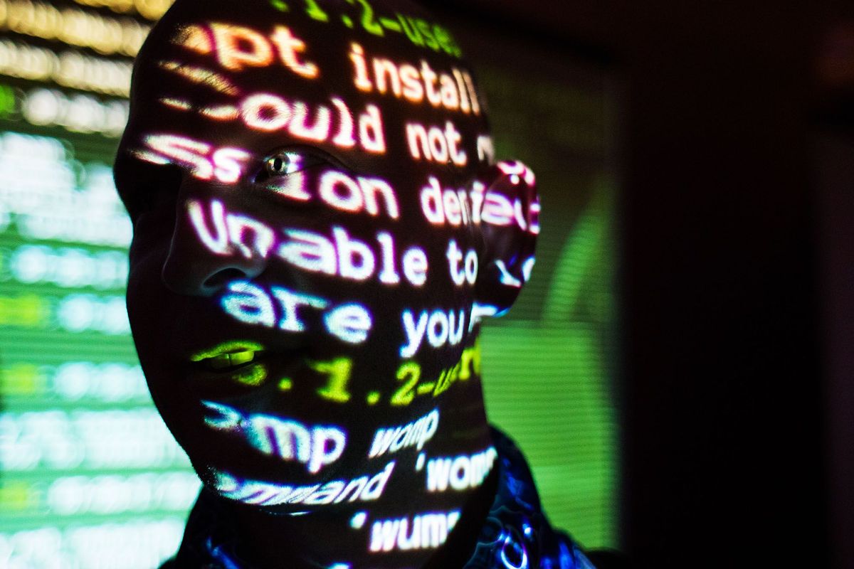 Een bezoeker van hackersconferentie DEF CON in Las Vegas loopt door het licht van een beamer De duizenden aanwezigen wonen er onder meer lezingen bij en diverse workshops van het schadevrij openen van gesloten deuren tot het inbreken in de software van autos