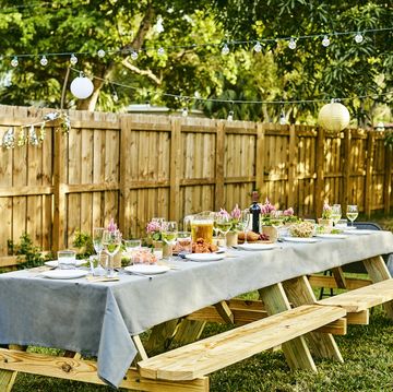 picnic table set up in a garden with floral decor and food