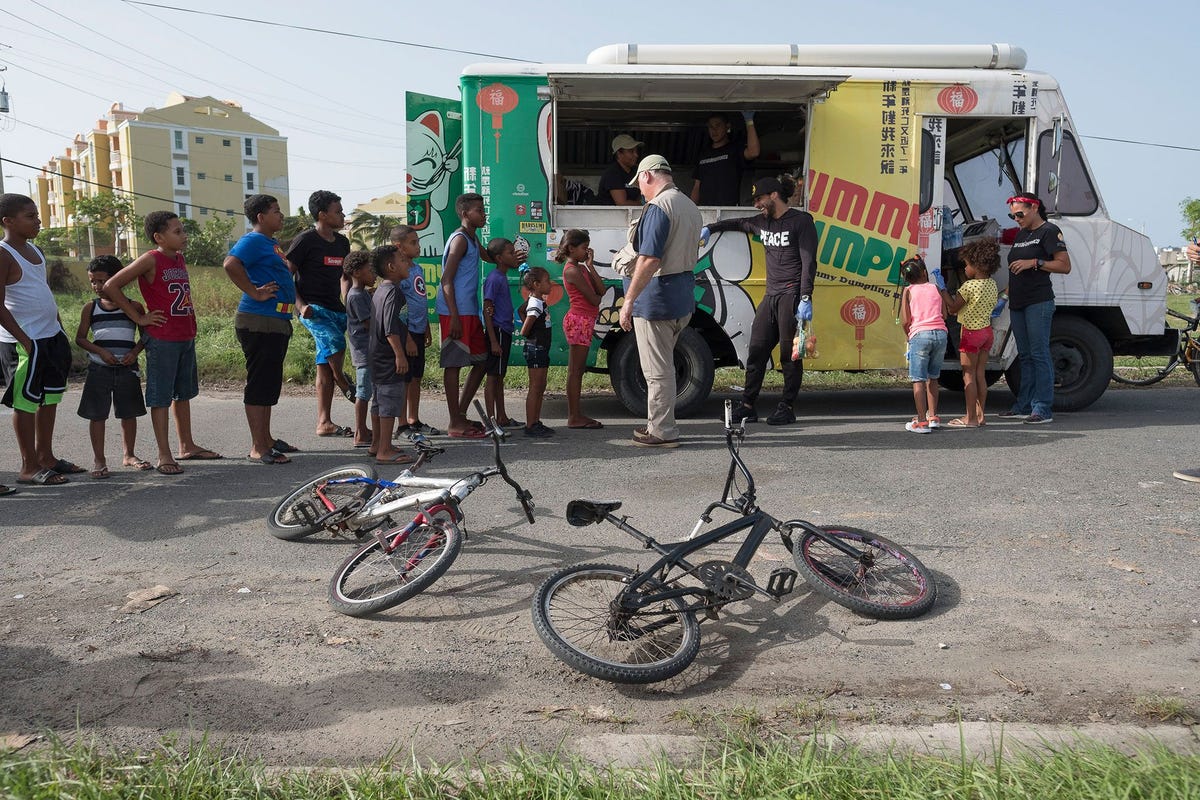 Chef Jos Andrs in het midden helpt met maaltijden serveren vanuit een food truck aan een rij mensen in Loza in Puerto Rico Food trucks speelden een belangrijke rol in de voedseldistributie van ChefsForPuertoRico