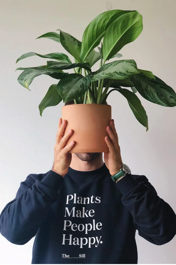 Man holding a plant in front of his face