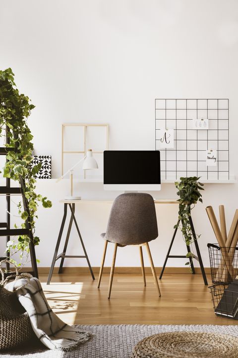 plant, white lamp and desktop computer on desk in freelancer's interior with grey chair real photo