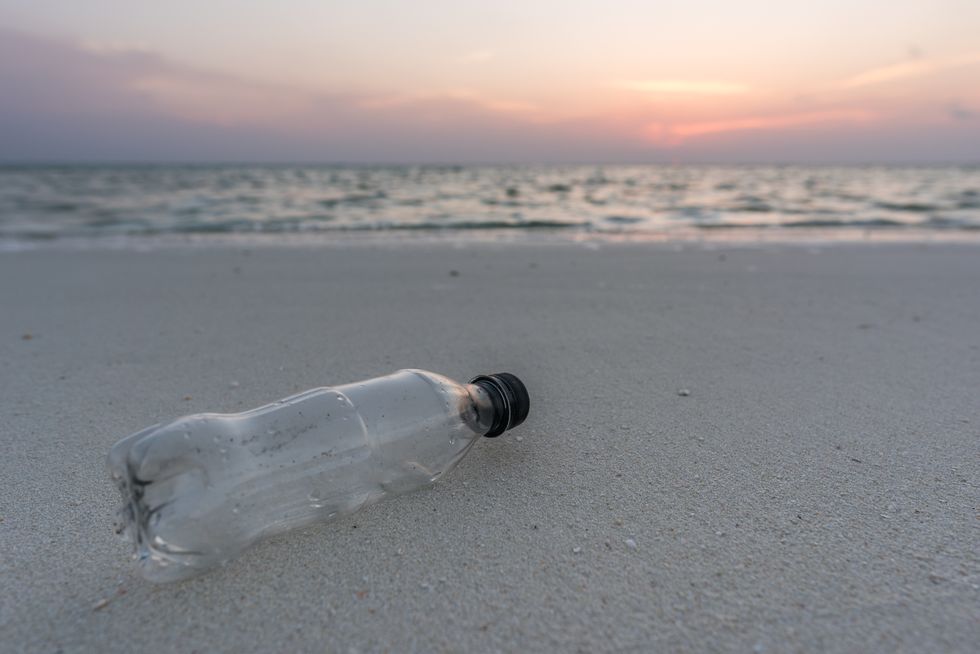 Plastic bottle on an empty beach at sunset