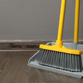 plastic broom with dustpan near grey wall indoors. space for text