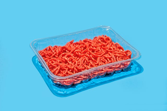 plastic tray with ground beef on blue background