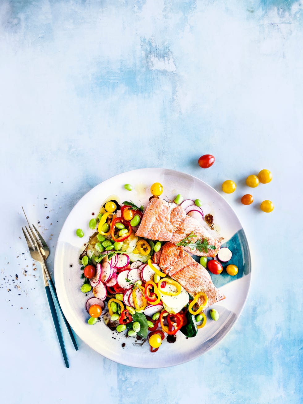 plate of fresh salad with fried salmon on blue background