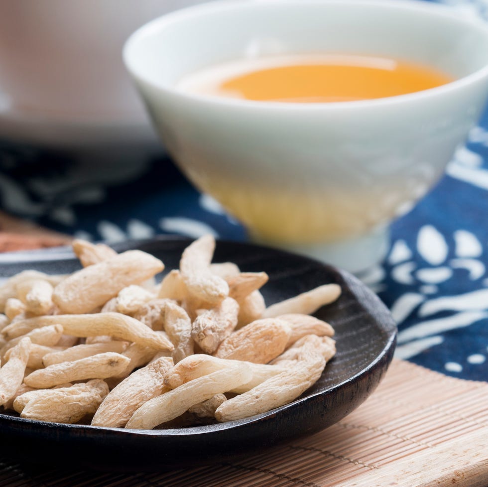 Plate of white ginseng roots lying in front of cup of tea