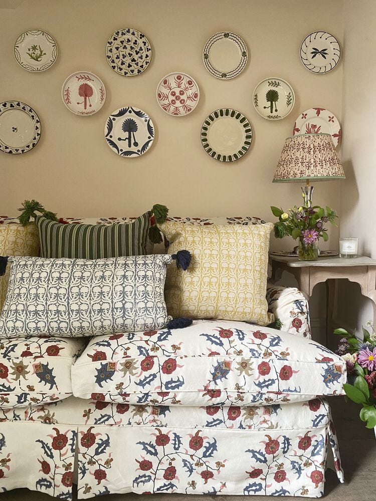 decorative sofa adorned with colorful cushions and wallmounted plates