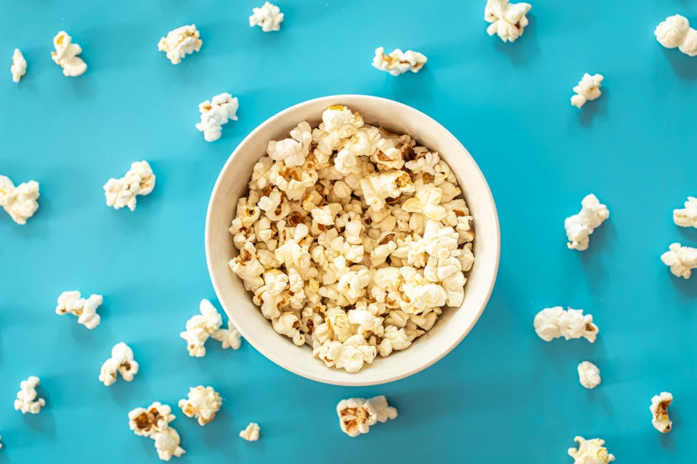 plate with popcorn on a blue background, flat lay