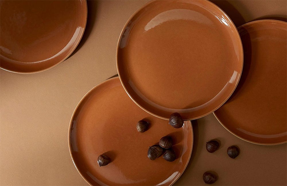 terracotta plates on a beige surface with scattered chestnuts