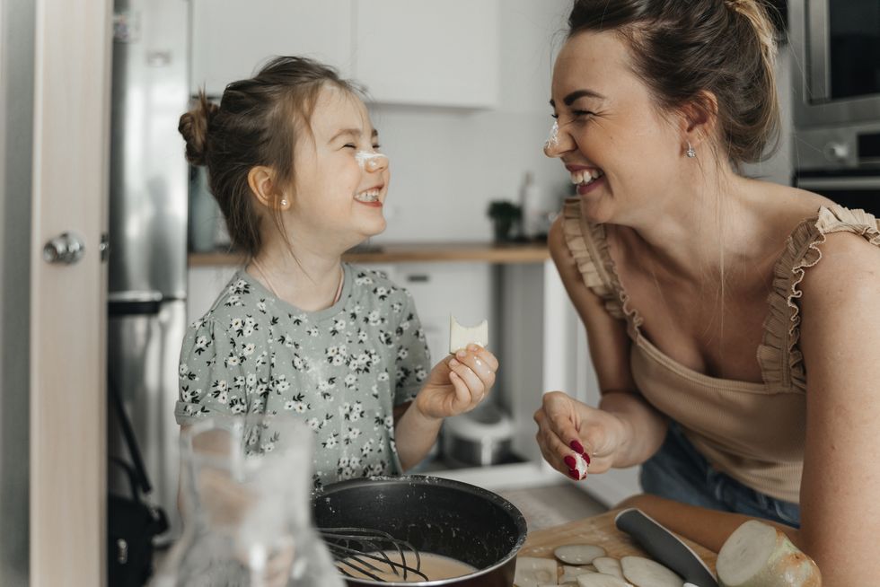 playful mother and daughter preparing food together in kitchen