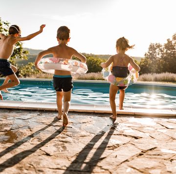 kid siblings jumping into a pool on a summer day