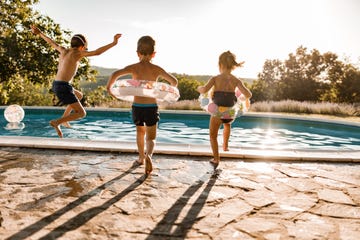 kid siblings jumping into a pool on a summer day