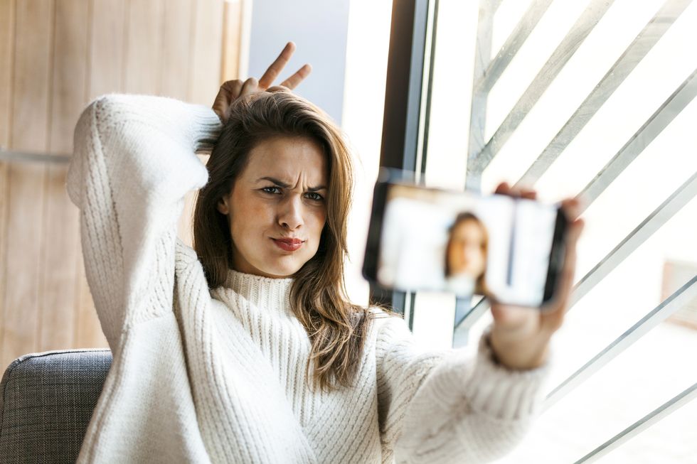 Playful young woman taking a selfie with cell phone