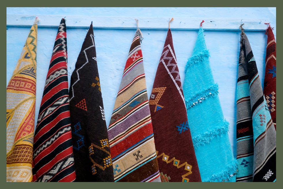 carpets and rugs are displayed outside a textile store in the blue city of chefchaouen, morocco