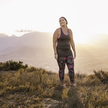 Plus size woman wearing sports clothing on mountain at sunrise