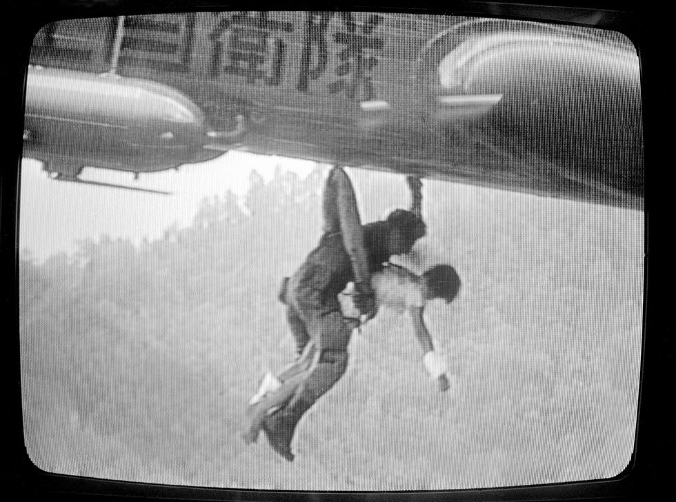 a survivor of the jal flight 123 crash is held by a defense force rescue worker as they are hoisted into a helicopter from the crash scene in tokyo, on tuesday, august 13, 1985 the plane went down monday, night in the mountains of central japan with 524 people on board this photo is from nhk television ap photoinoue