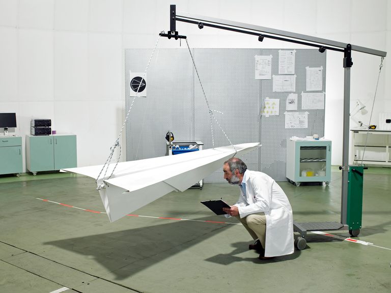a scientist inspects a large paper airplane
