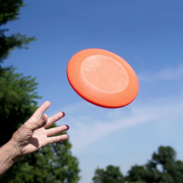 a frisbee leaves a hand against a blue sky background