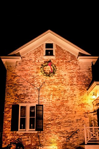 kh3bb6 christmas wreath on a historical brick house at night with a spotlight, cranbury, new jersey, usa, vintage colonial christmas house garden snow