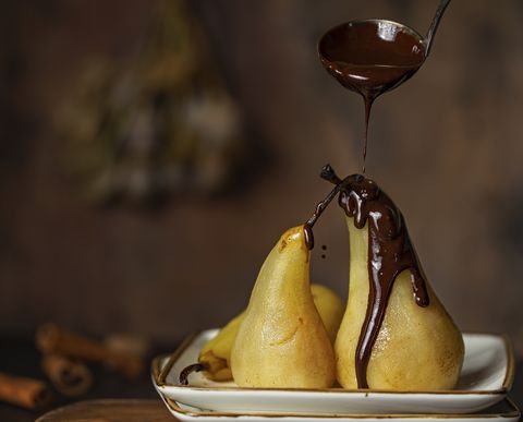 poached pears with chocolate sauce or glaze process of glazing brown rustic wooden background