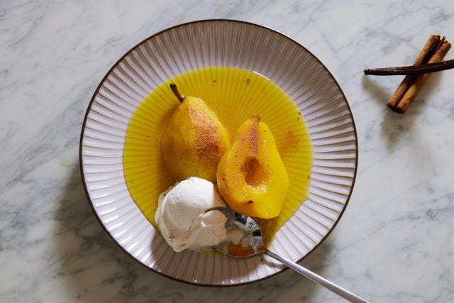golden yellow poached pears in poaching liquid with vanilla ice cream on a pink plate golden yellow poached pears in poaching liquid with vanilla ice cream on a pink plate