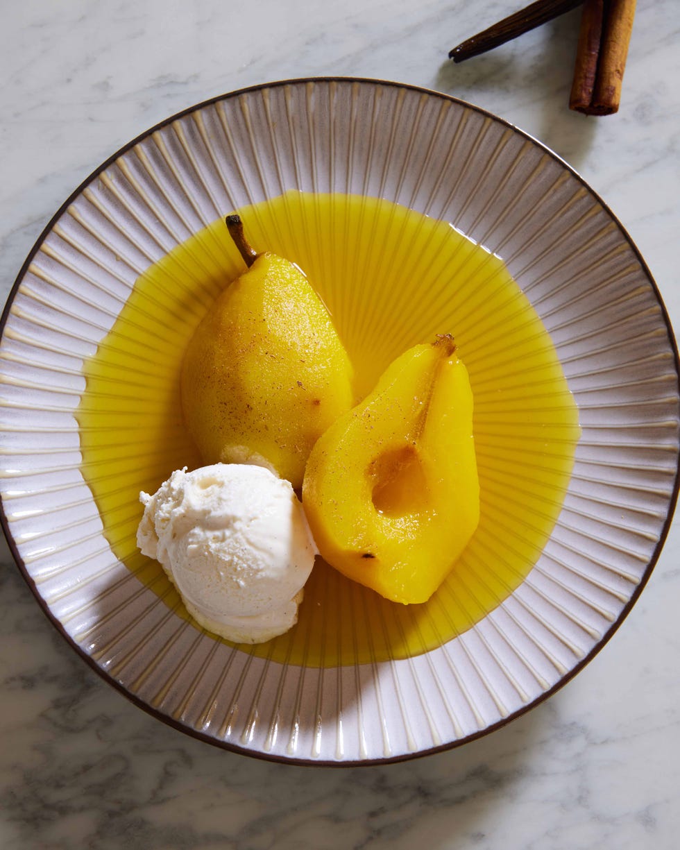 golden yellow poached pears in poaching liquid on a pink plate