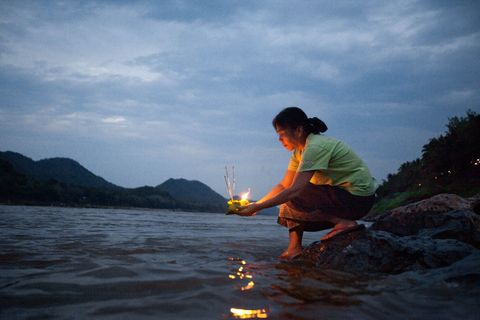 In Laos wordt Nieuwjaar halverwege april gevierd Op deze foto uit de National Geographic van april 2010 een speciaal nummer over water is te zien hoe een vrouw een brandende offerande brengt aan de rivier de Mekong die door de Laotianen de moeder van alle wateren wordt genoemd