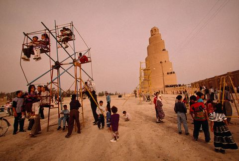 Een speeltuin vermaakt gezinnen die een bezoek brengen aan de Grote moskee van Samarra in Irak deze is op de achtergrond te zien De spiraalvormige minaret hier te zien in de late jaren 1990 dateert uit het jaar 851 Het liep schade op door bombardementen in 2005